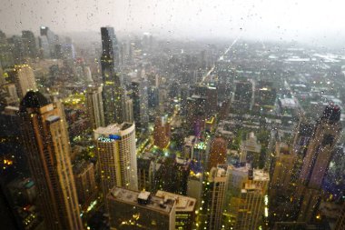 Penceresinde yağmur damlaları olan büyük bir şehirdeki gökdelenlerin ya da gökdelenlerin manzarası
