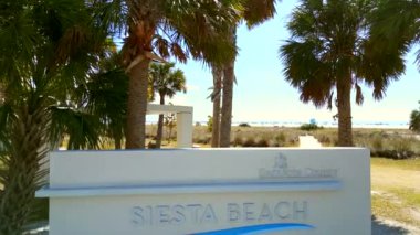 Aerial flyover Sarasota Beach sign on Siesta Key to reveal dunes and beach 4k