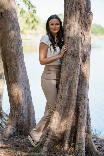 一个美丽而快乐的女人躺在湖边一棵树旁的照片 — 图库照片