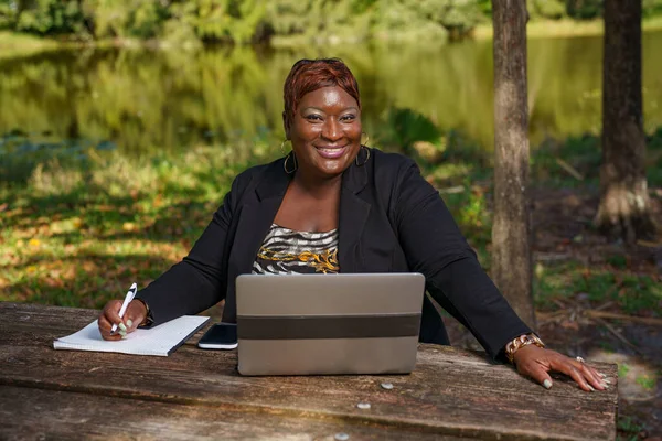 CEO of her company working outdoors in a nature park scene with laptop