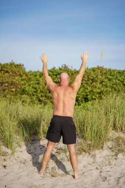 Sahilde gökyüzüne uzanan bir adamın arka fotoğrafı.