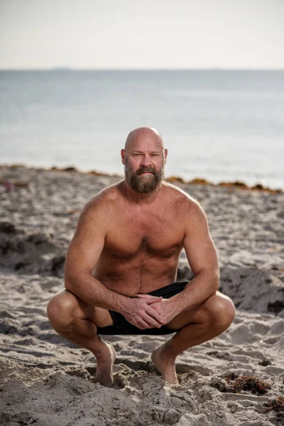 Uomo Accovacciato Sulla Sabbia Della Spiaggia — Foto Stock