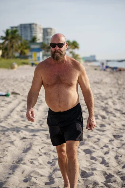 Macho硬汉在海滩上散步男人戴着太阳镜 没穿衬衫 — 图库照片