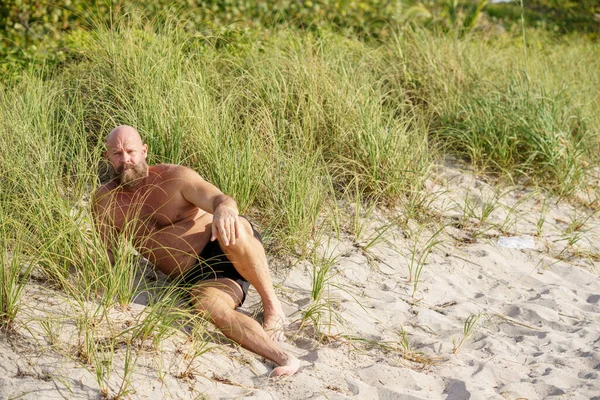 一个英俊的男人躺在佛罗里达沙丘边的海滩上 — 图库照片