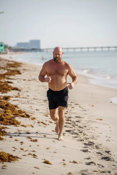 在海滩上奔跑的硬汉白人 — 图库照片