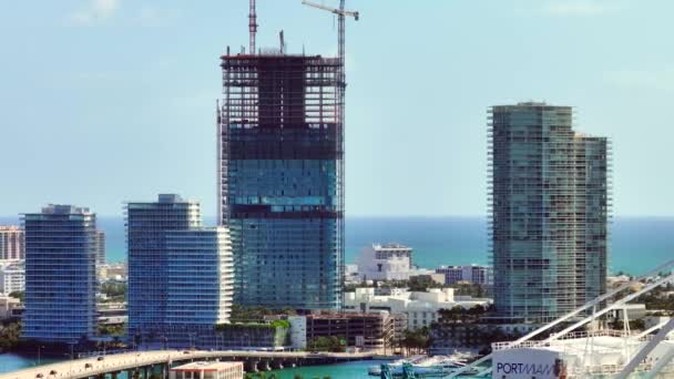 Miami Beach, FL, USA - September 4, 2023: Aerial telephoto 7x zoom video Five Park Miami Beach blocked by Port Miami cranes entering shot