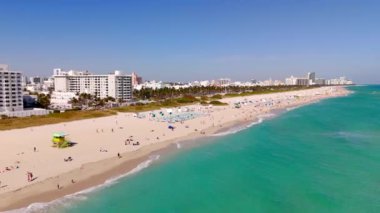 Miami kış kaçamağı. 4K hava aracı videosu Miami Beach, Florida, ABD. Miami Sahili manzarası, cankurtaran kuleleri ve denizde yüzen turistler.
