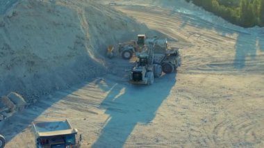 Miami, FL, ABD - 29 Ocak 2025: Tırtıl tekerlek yükleyicileri taşları beyaz bir taş ocağında bir çöp kamyonuna yüklüyorlar