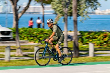 Key Biscayne Miami, FL, ABD - 8 Mart 2025: Miami Key Biscayne 'de bisiklet süren uzun pozlu fotoğrafçı