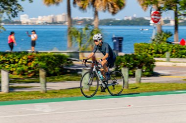 Key Biscayne Miami, FL, ABD - 8 Mart 2025 Miami Key Biscayne Florida 'da bisiklet süren yavaş panjurlu bulanık adam