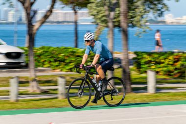 Key Biscayne Miami, FL, ABD - 8 Mart 2025 Miami Key Biscayne Florida 'da bisiklet süren yavaş panjurlu bulanık adam