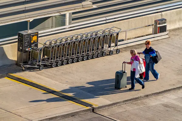 Fort Lauderdale, FL, ABD - 13 Mart 2025: İki kadın tatil uçağına yetişmek için havaalanına yürüyorlar
