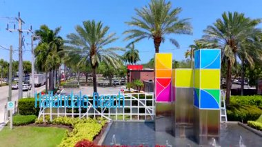 Hallandale Sahili hoş geldin tabelası, I95. İnsansız hava aracı havalanıyor. Kasaba ve okyanusu ortaya çıkarıyor.