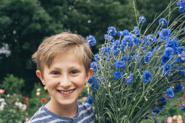Bahçedeki mutlu sarışın çocuk elinde bir buket çiçekle