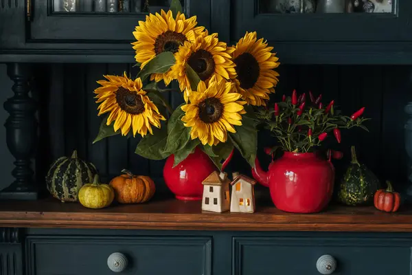 Beautiful sunflowers in a vase, autumn decor with candles and pumpkins