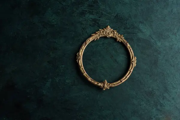 Vintage openwork round bronze metal frame on the old wall background, empty picture frame mockup