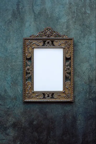 Vintage openwork bronze metal frame on a blue and green old wall with drips, texture background, empty picture frame mockup