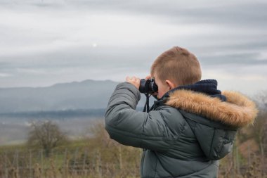 Çocuk dürbünle doğayı araştırıyor. Çocuk doğada vakit geçirir, yürür ve evin dışında eğlenir, baharda boş vakit geçirir ve eğlenir.