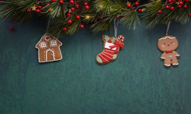 Noel arkaplanı, mevsimlik dekor ve kurabiyelerle dolu. Işıklarla süslenmiş köknar dalları ve böğürtlenli kurabiyeler