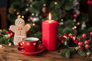 Masada şenlikli bir dekor, mumlar ve kurabiyeli bir fincan çayla Noel arkaplanı.