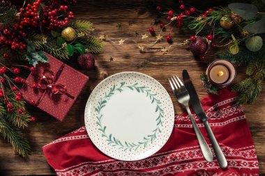 Masa dekoru, yemek tabağı, mum ve hediyeli Noel arkaplanı.
