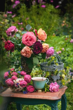 Bir vazoda İngiliz gülleri ve bahçede bir fincan çay.. 