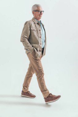 Elleri ceplerinde ve başı yukarıda yürüyen sıradan bir adamın yan görüntüsü.