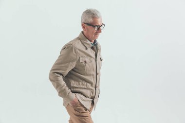 Yaşlı sıradan bir adam elleri ceplerinde yürüyor ve aşağıya bakıyor, kasvetli hissediyor.