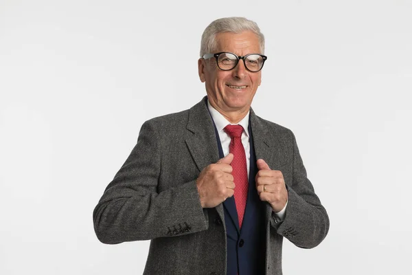 Old business man feeling happy to wear his new coat and smiling at the camera against grey background