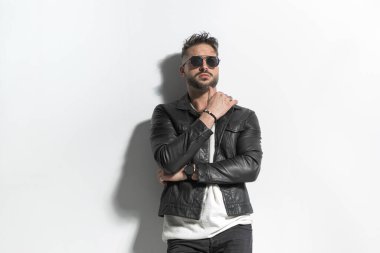 Islak saçlı, kollarını kavuşturan ve stüdyoda gri arkaplan önünde havalı poz veren kendine güvenen bir manken.