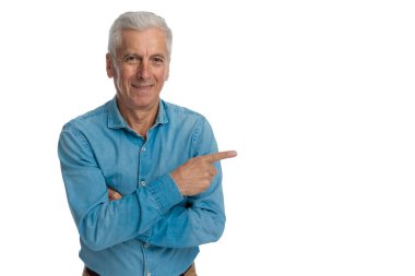 Beyaz saçlı beyaz yaşlı adam mutlu, gülümsüyor ve beyaz arka planda stüdyoda kendini gösteriyor.