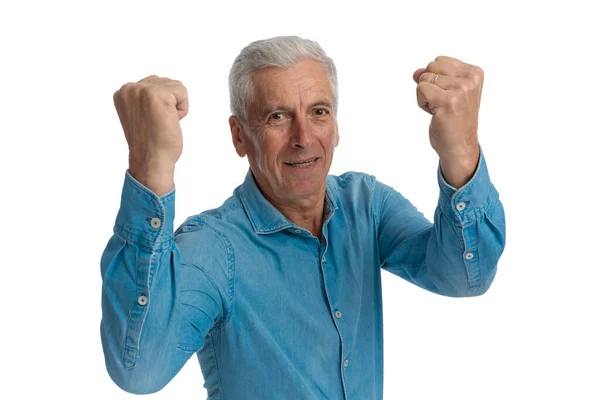 穿着斜纹棉布衬衫的随意老人举着拳头 欢呼胜利 微笑着 在工作室的白色背景面前感到自豪 肖像画 — 图库照片