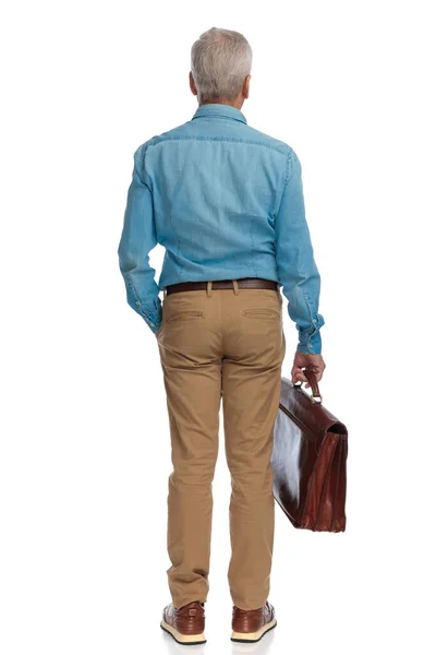 손에는 가방을 손에는 주머니에 배경에 고립된 남자의 뒷모습 — 스톡 사진