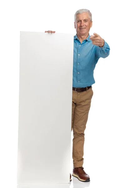 60代の男性が指を指差して白い板をスタジオの白い背景の前に出し — ストック写真