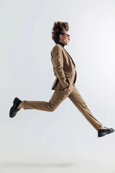 Stüdyonun Gri Arka Planının Önünde Elleri Ceplerinde Havaya Zıplayan Genç — Stok fotoğraf