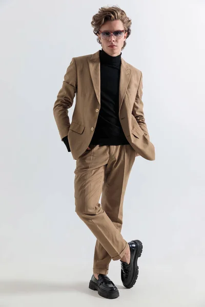 全身写真の若い男ですスーツを手にポケットに手を取りスタジオで灰色の背景の前でポーズ — ストック写真