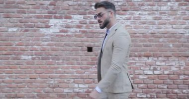 Zarif bir Latin erkeğin yürüdüğü, arkasına baktığı ve koşmaya başladığı, güldüğü ve dışarıda eğlendiği bir yan görüntü.