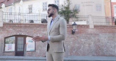 Zarif moda işadamının avuçlarını ovalarken, güneş gözlüğü yerleştirirken, etrafa bakınırken ve el ele yürürken çekilmiş bir video projesi.