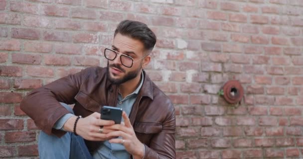 Confident Latin Guy Holding Mobile Reading Emails Sitting Elbow Knee — Stock Video