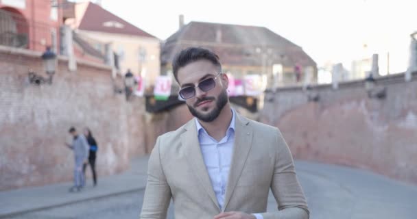 幸せな若い実業家が古い中世の町の前でサングラスを引いたり笑ったり — ストック動画