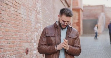 Romanyalı bir ortaçağ kasabasında, duvarın önünde havalı bir adamın, deri ceketini ayarlayıp kollarını kavuşturduğu bir video projesi.