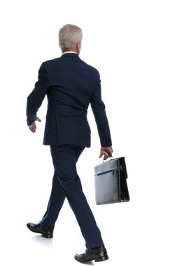 rear view and full body picture of an old business man walking one way while looking the other way with his briefcase in hand