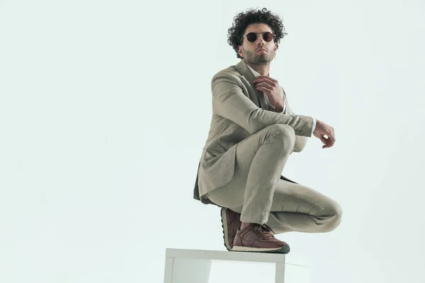 Confident Lebanese Businessman Wearing Sunglasses Adjusting Suit Collar Crouching Elbow — Stock Photo, Image