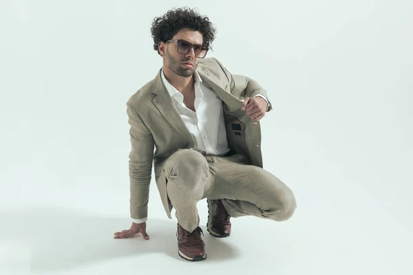 Handsome Greek Guy Sunglasses Adjusting Pulling Suit While Crouching Front — Stock Photo, Image