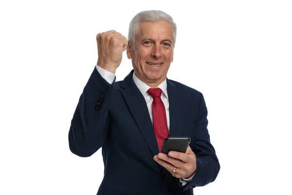 60代のビジネスマンが成功を祝いながら電話でメッセージを書いています — ストック写真
