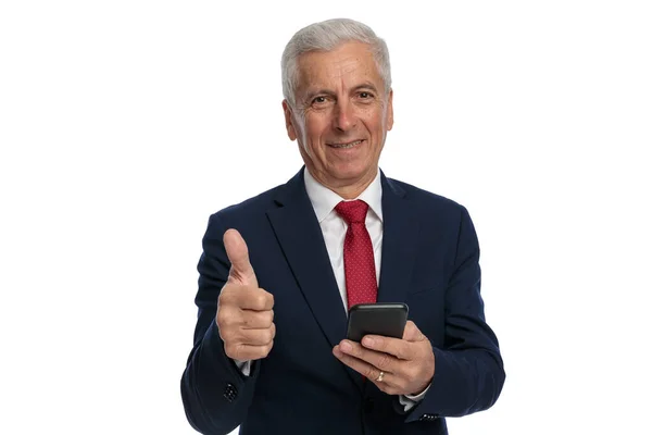 親指を上げながら彼の電話で古いビジネスマンのテキストメッセージ — ストック写真