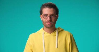 project video of sexy man with glasses smiling, flirting and sending kisses in front of blue background in studio