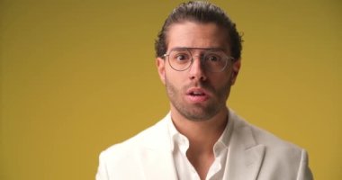 project video of disappointed young man in white shirt with eyeglasses being upset for not winning and hiding on yellow background