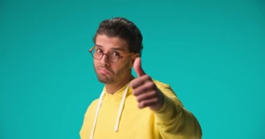 curly hair guy with glasses making ok gesture and looking through, being happy and smiling on blue background in studio