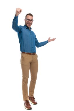 full body picture of excited young man holding fist in the air and celebrating the victory,  laughing and walking on white background in studio